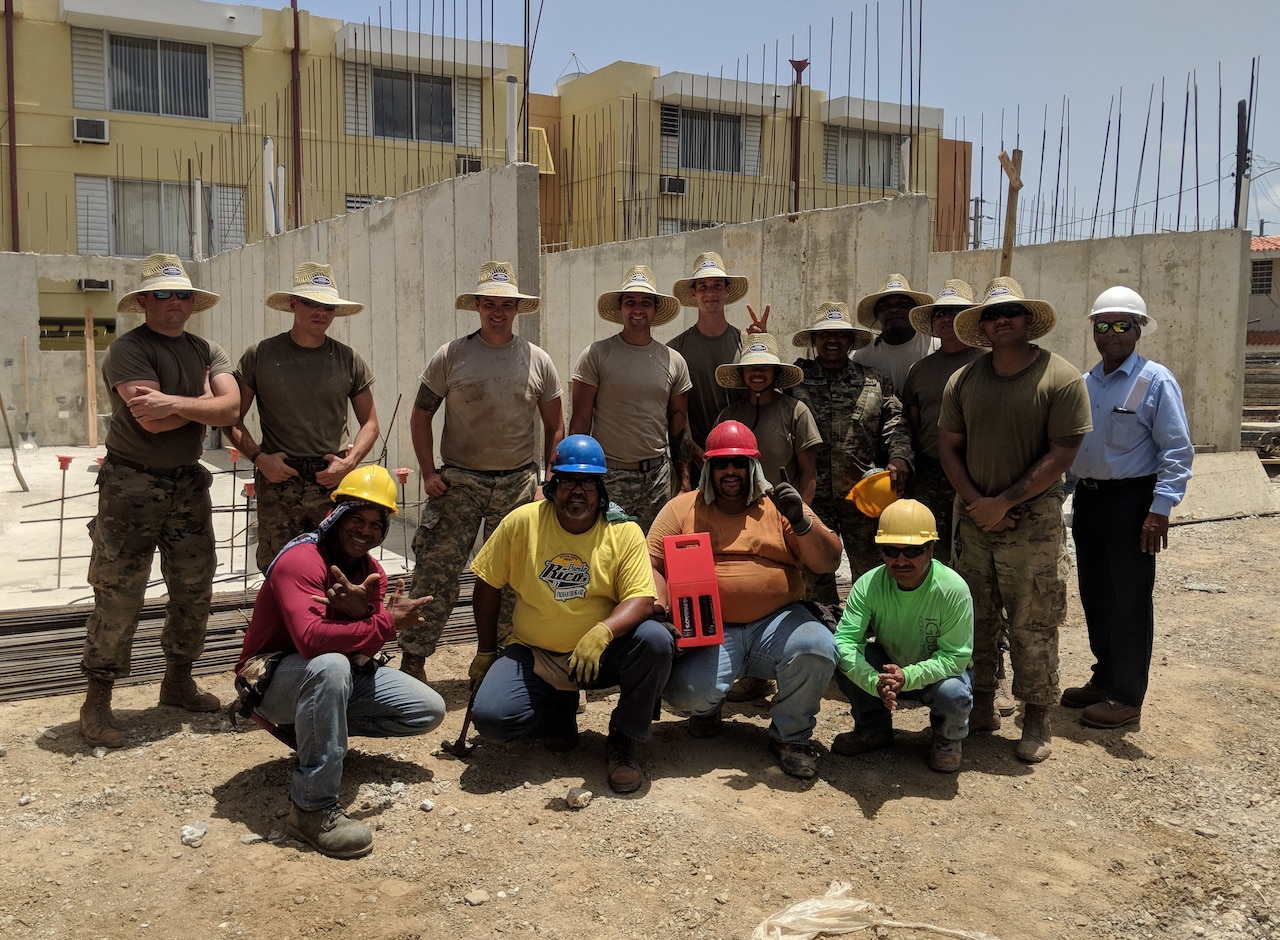 Soldier pose in front of a house they are building.