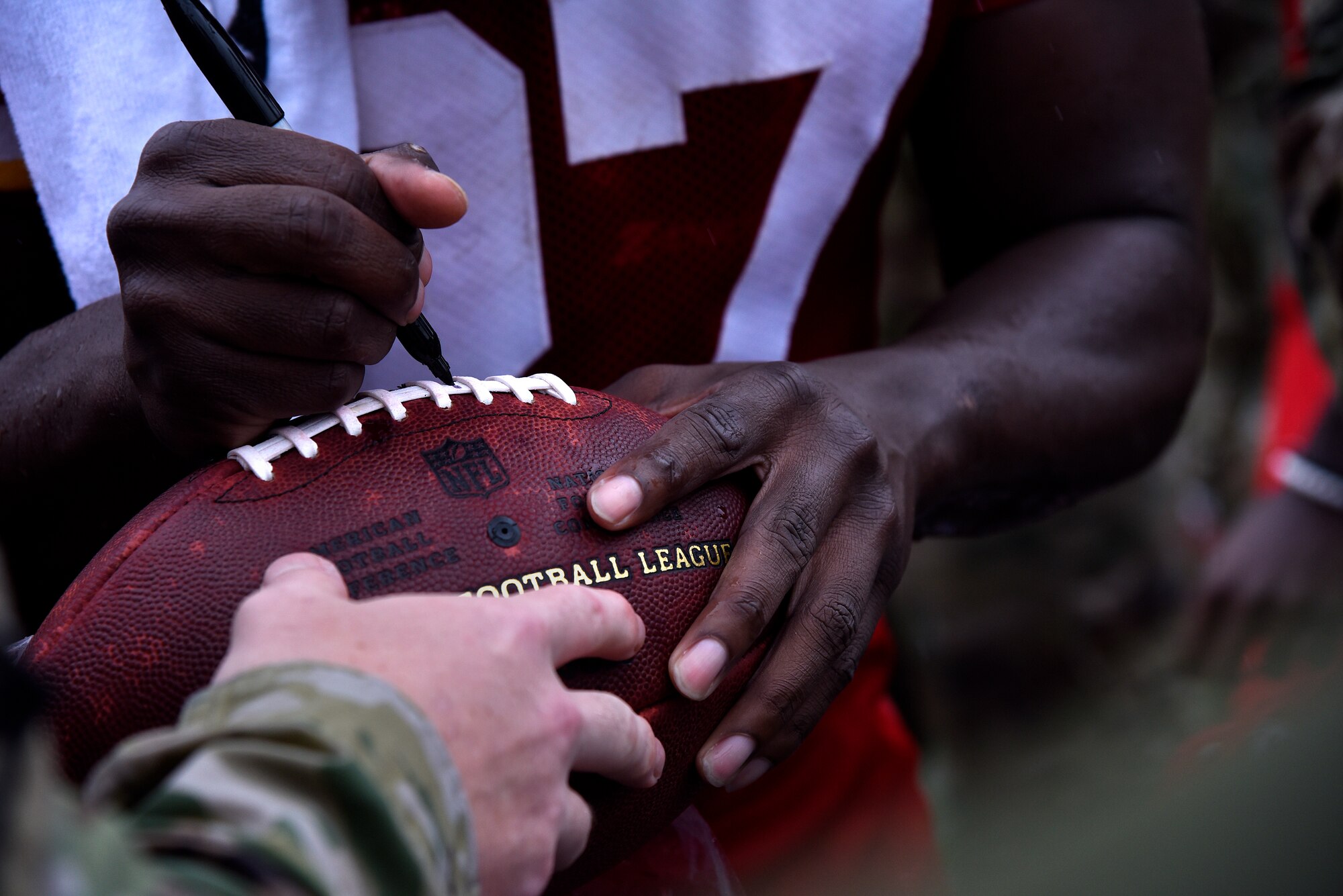 A Kansas City Chiefs player signs a football after military appreciation day at the Chiefs training camp in St. Joseph, Mo., Aug. 14, 2018. The Chiefs invited military members from across Kansas and Missouri  to watch their final training camp practice as well as meet and greet the players.