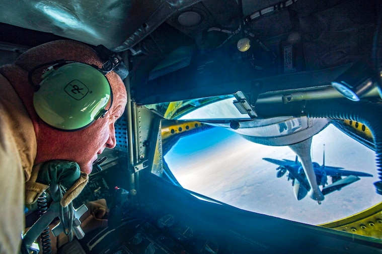 An airman watches an F-15 Eagle through a plane window during refueling.