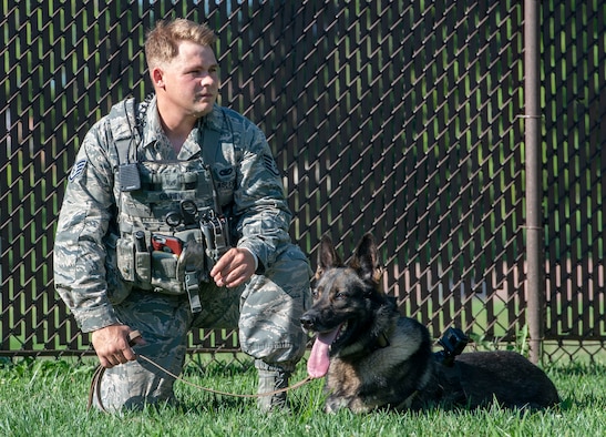 Staff Sgt. Christopher O’Brien, 375th Security Forces Squadron K-9 handler sits with his Military Working Dog, Irk, at the 375th SFS kennel  July 25, 2018.