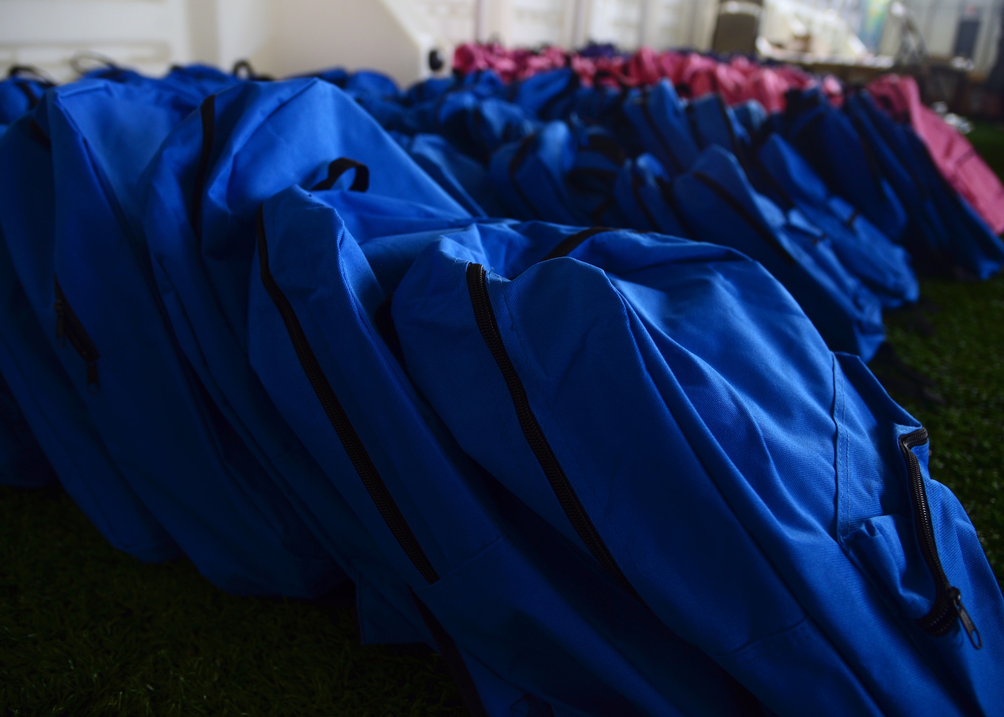 Rows of backpacks sit ready for distribution at the Back-to-School Roundup in the Pride Hangar on Ellsworth Air Force Base, South Dakota, August 18, 2018. More than 500 backpacks and lunchboxes were provided to Ellsworth families. (U.S. Air Force photo by Senior Airman Denise M. Jenson)