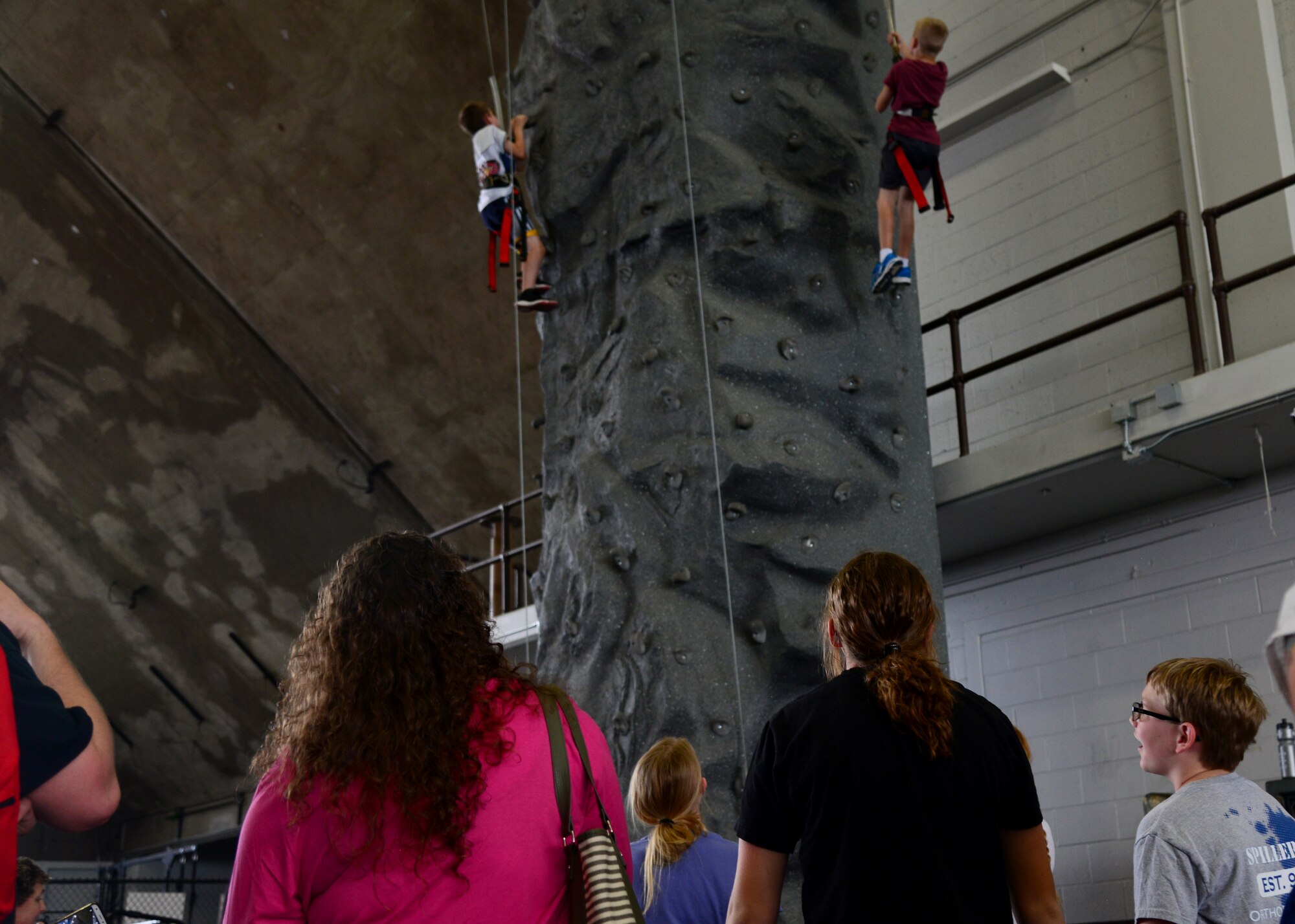 Parents and family members watch children climb up a rock wall inside the Pride Hangar on Ellsworth Air Force Base, South Dakota during the Back-to-School Roundup, August 18, 2018. More than 500 families were given free backpacks and school supplies, all of which were provided by Operation Homefront, a non-profit that provides for military families. (U.S. Air Force photo by Senior Airman Denise M. Jenson)