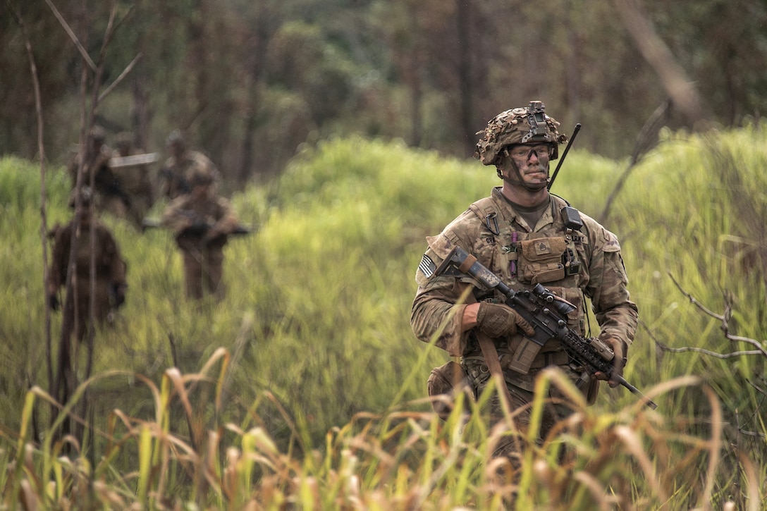 Soldiers maneuver through tall grass during a combined arms live-fire exercise.