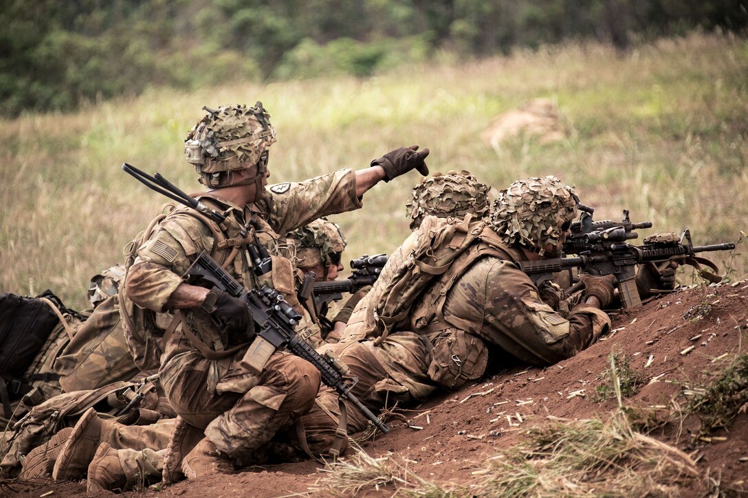 A soldier directs his squad in the direction to provide suppressive fire.