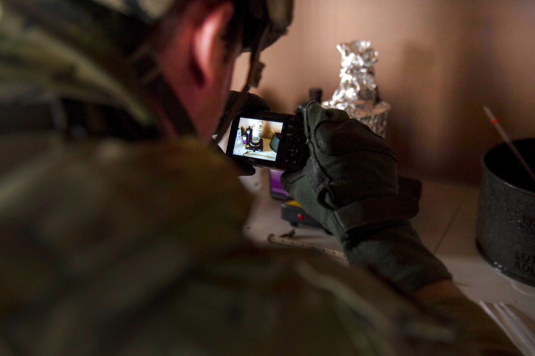 An Australian soldier takes photographs of a homemade explosive device.