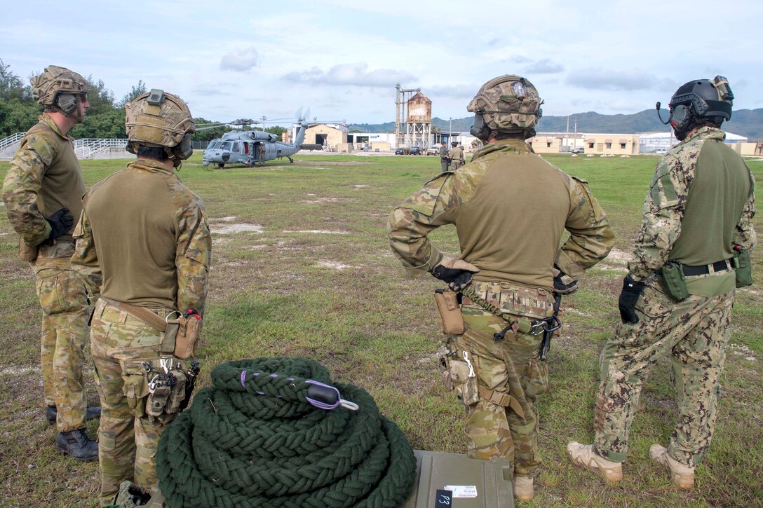 A U.S. sailor and Australian soldiers prepare their gear before conducting fast-rope training.