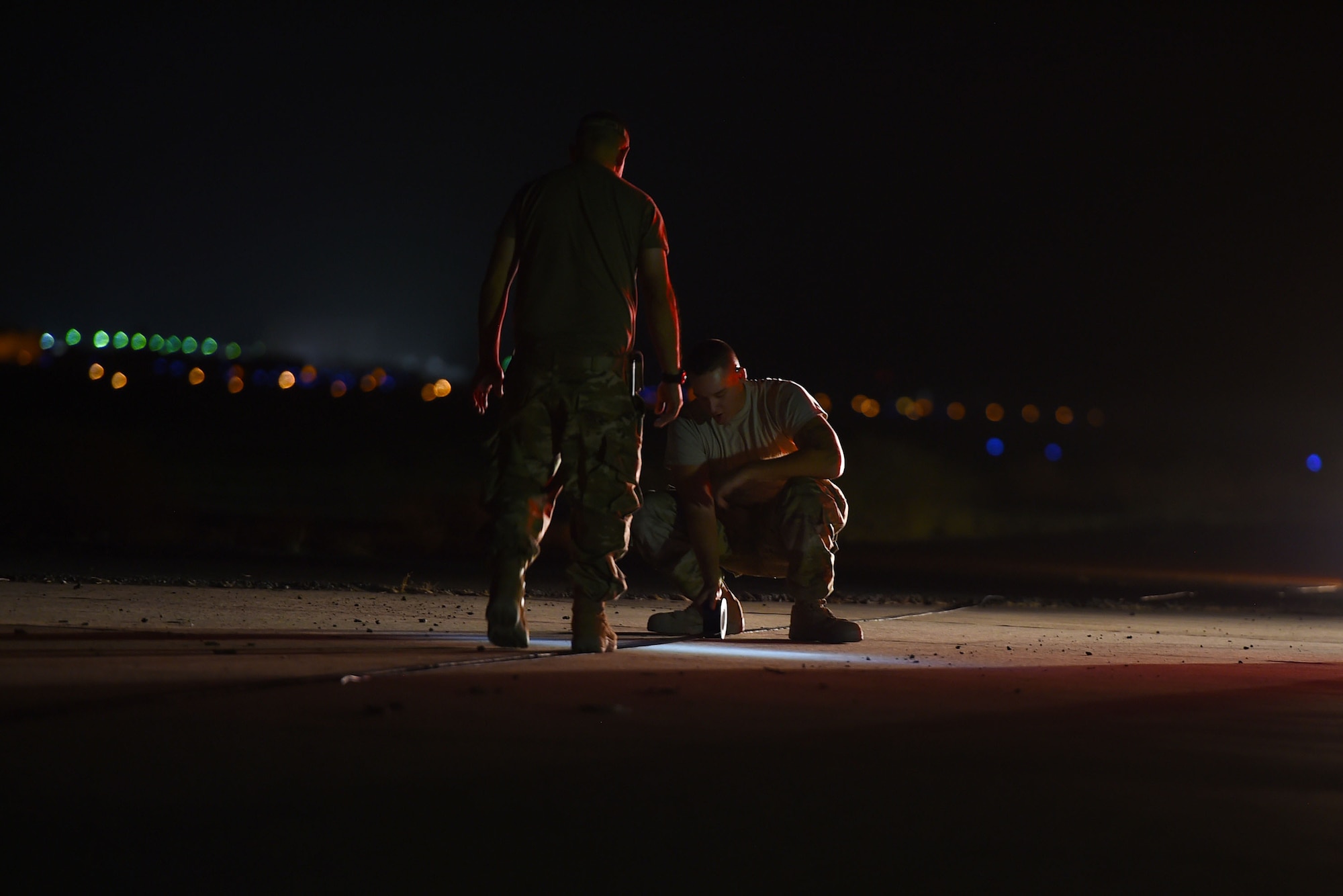 Two Airmen work in the dark on the flightline
