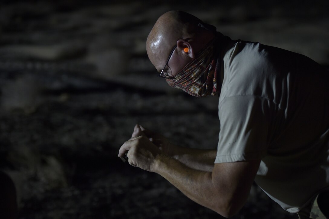 A Airmen uses his hands to signal while working outside at night