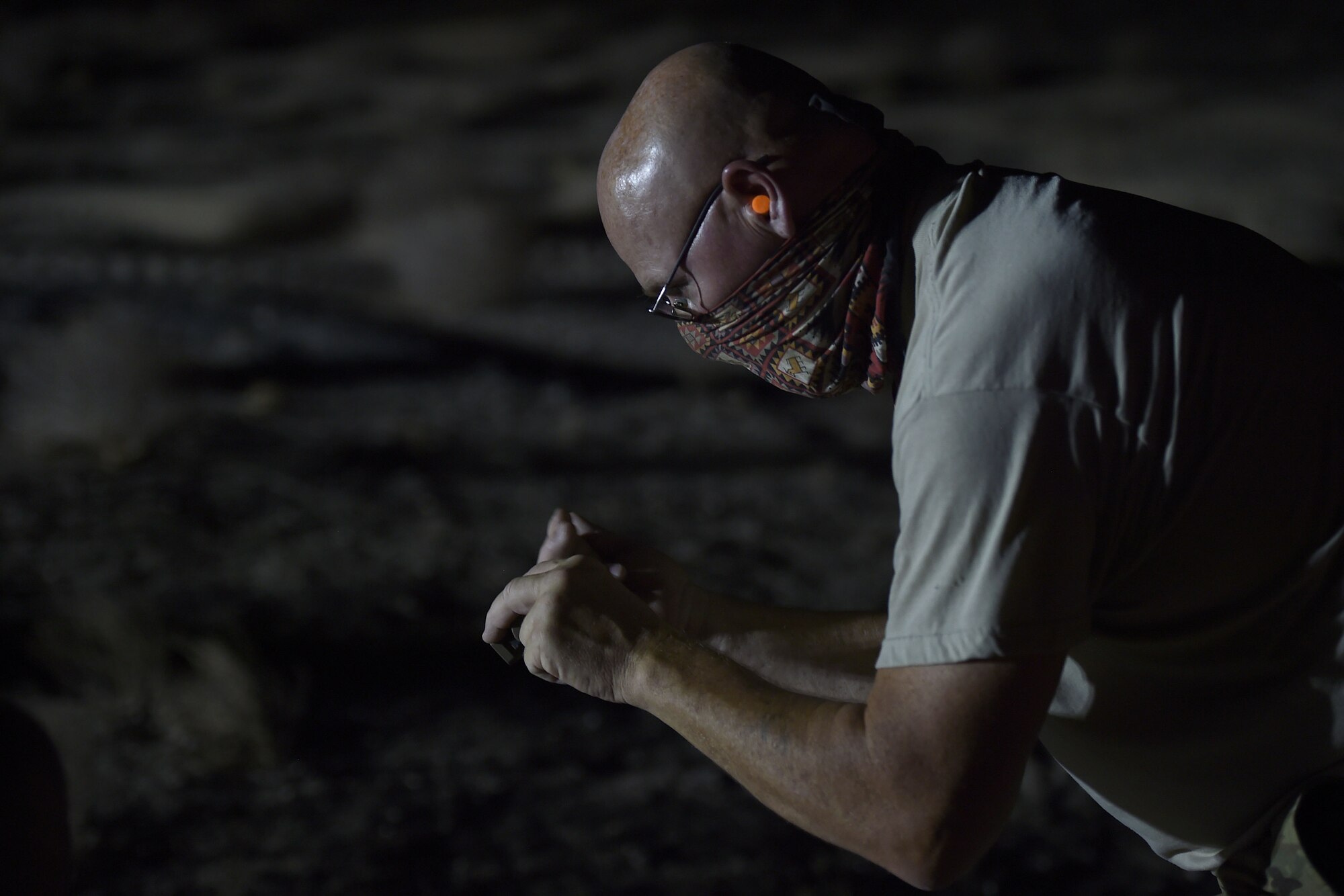 A Airmen uses his hands to signal while working outside at night