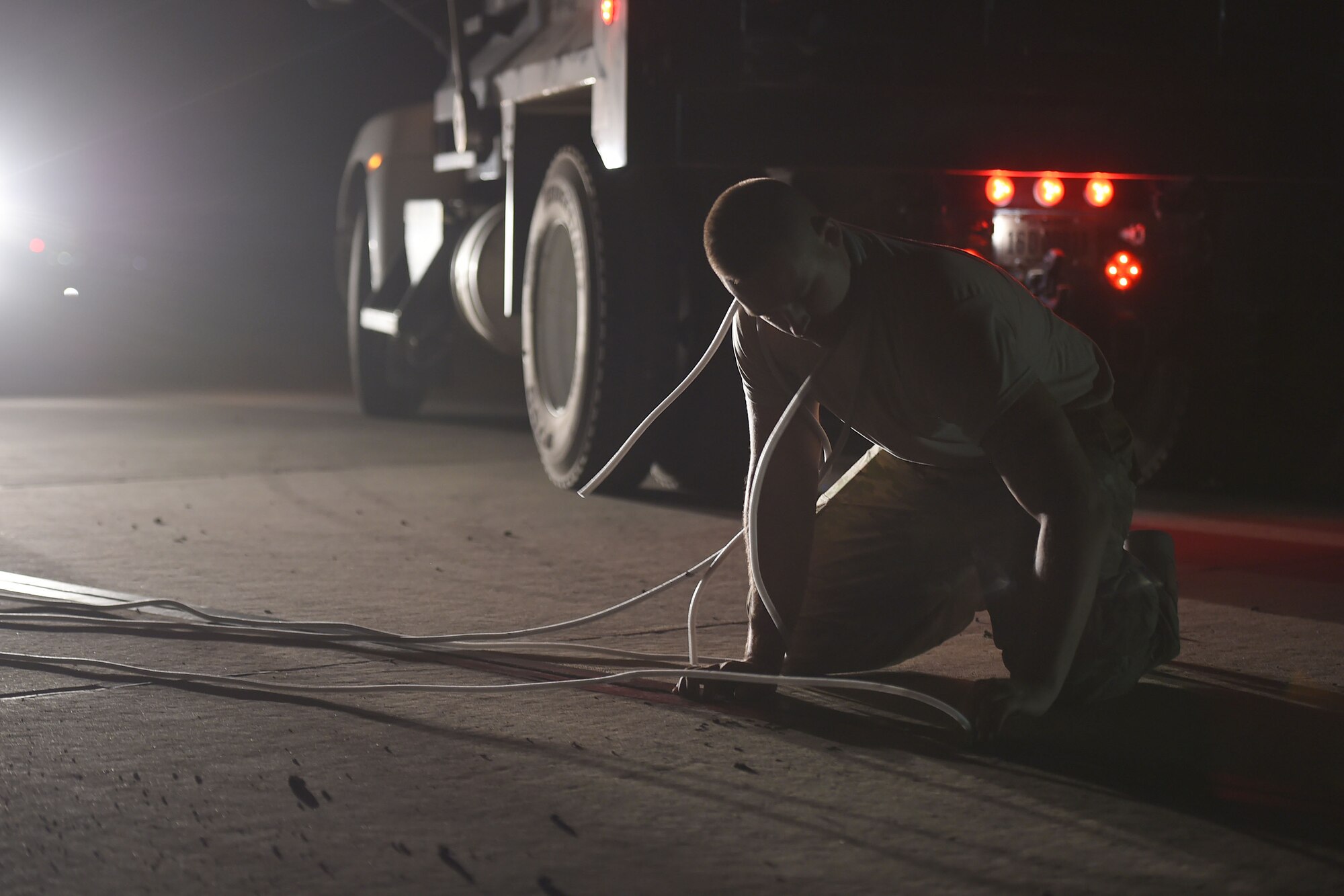 An airman works on the runway at night