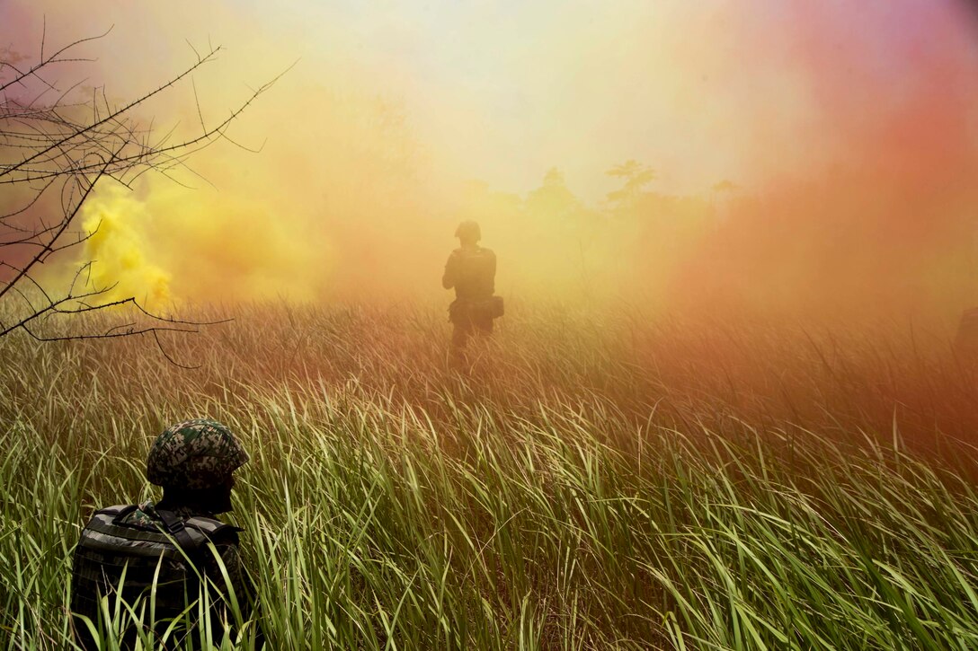 Two soldiers with the Malaysian Armed Forces find concealment in smoke during an amphibious raid with U.S. Marines from the 13th Marine Expeditionary Unit during Cooperation Afloat Readiness and Training 2018, August 16, 2018. CARAT Malaysia, in its 24th iteration, is designed to enhance information sharing and cooperation, build mutual warfighting capability and support long-term regional cooperation enabling both partner armed forces to operate effectively together as a unified maritime force.