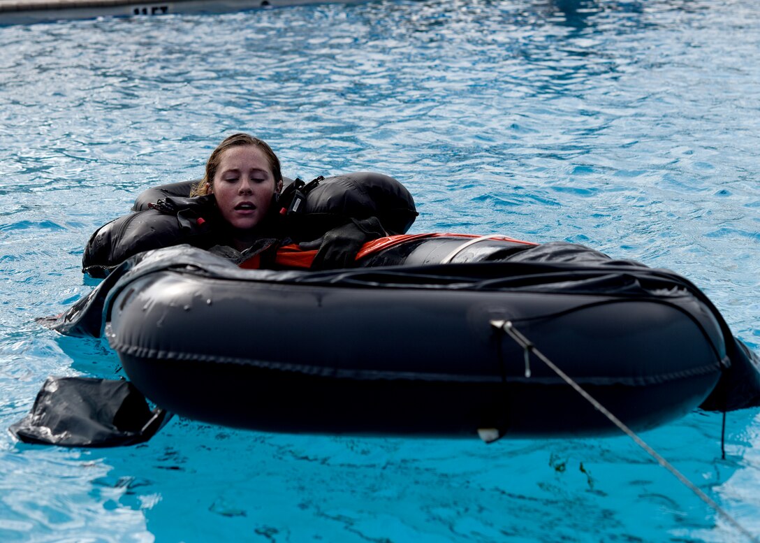 An airman sims towards a raft while wearing full aircrew gear.