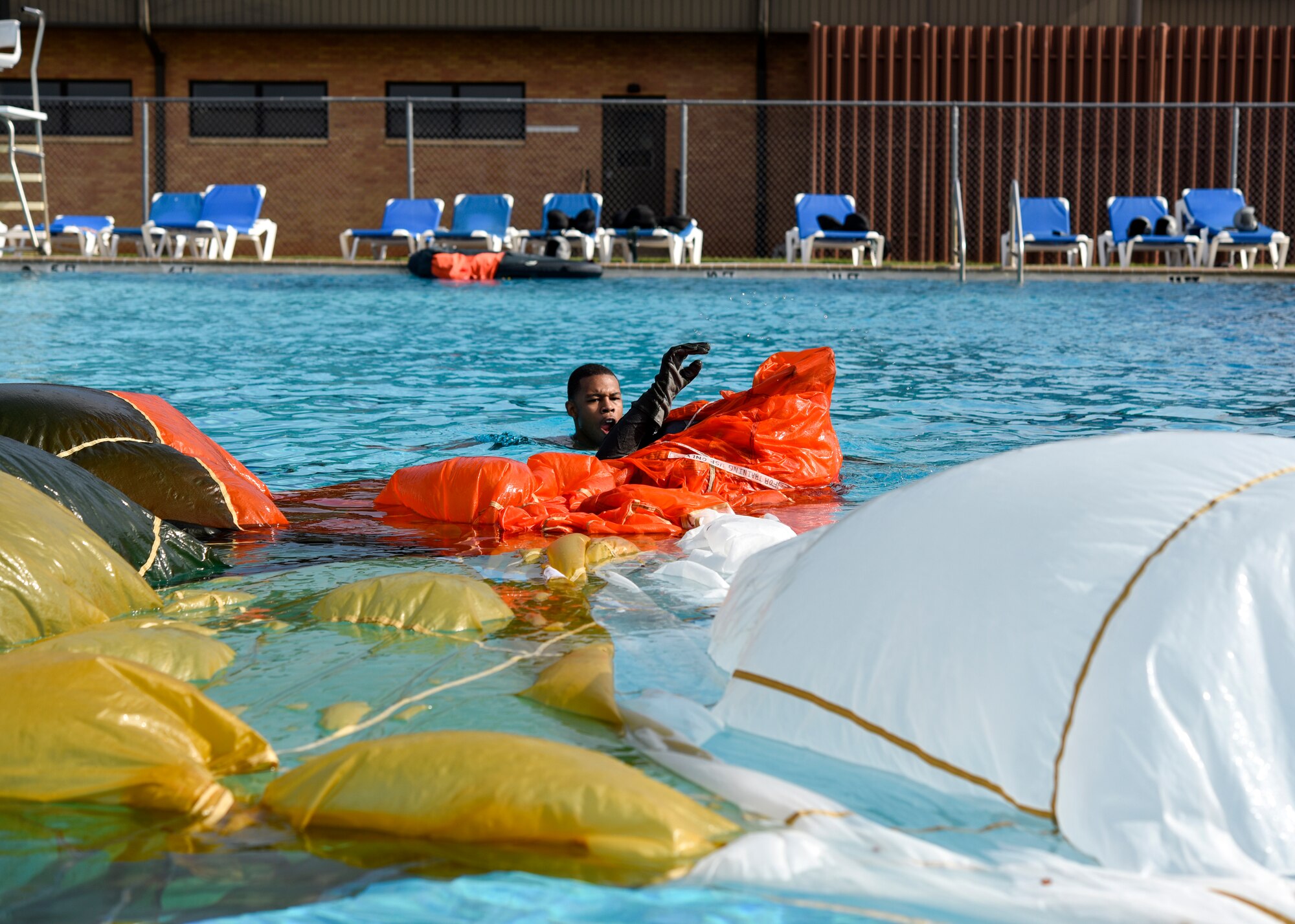 An airman gasps for air as they escape the parachute, during the exercise where a parachute is engulfed over the pilot in the water survival emergency training.