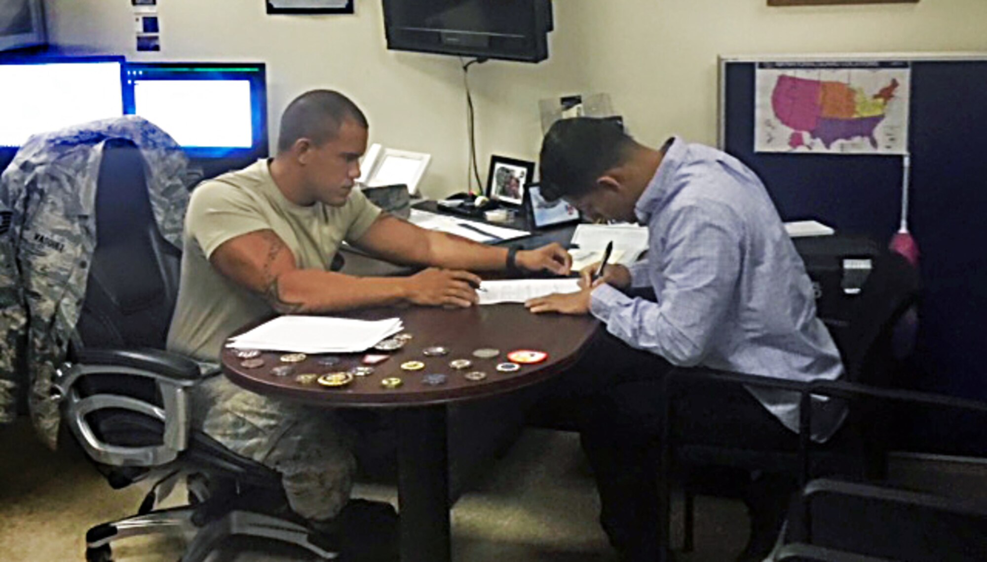 A picture of Tech. Sgt. Freddy Vasquez assisting a new recruit with paperwork.