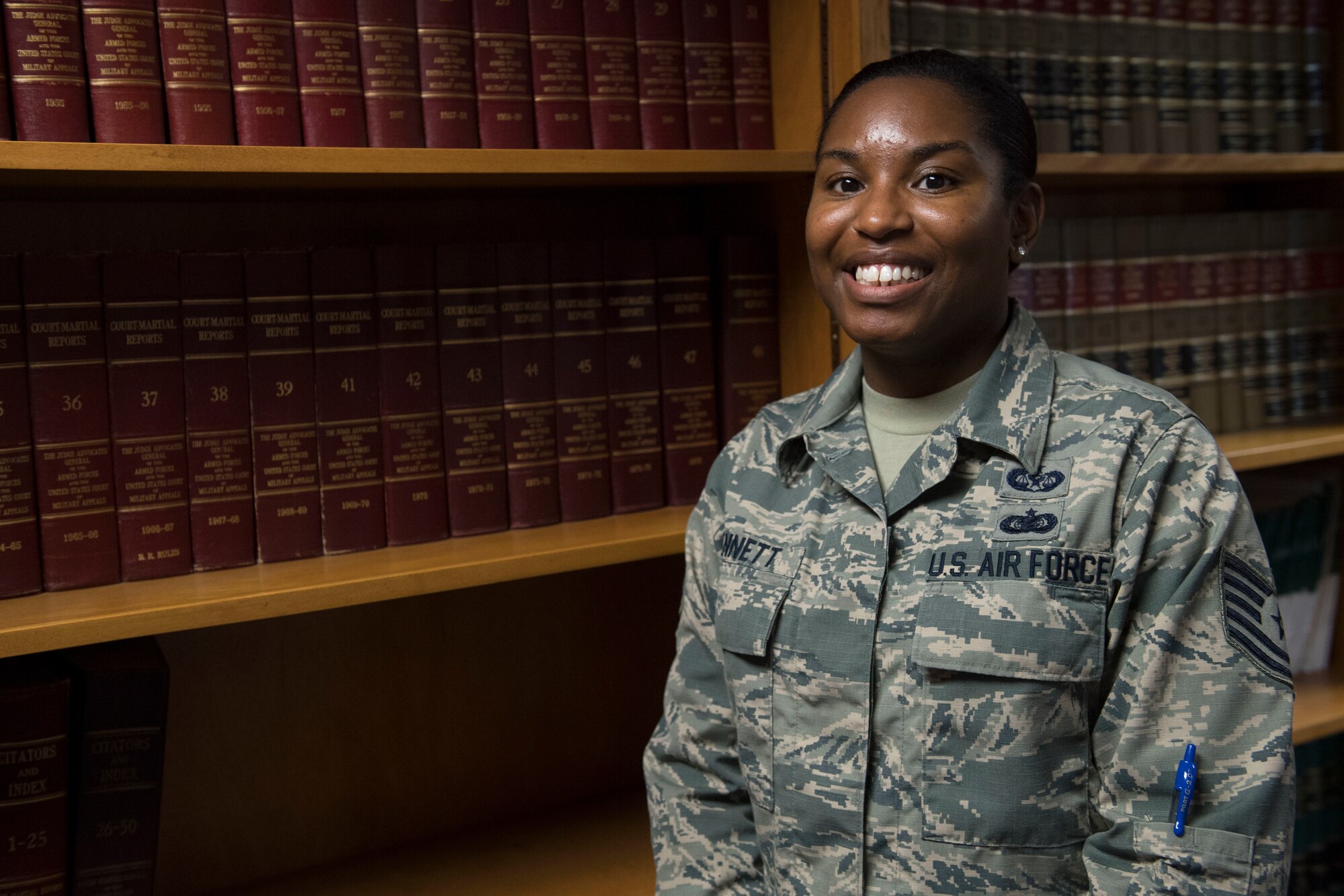 Woman poses for photo in front of bookshelf.