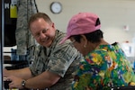 U.S. Air Force Col. William Bray, the commander of the 181st Medical Group, 181st Intelligence Wing of the Indiana Air National Guard, speaks to a community member during a physical screening at the Mitchell Pauole Community Center in Molokai, Hi., Aug. 13, 2018.