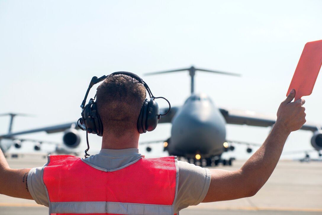 Senior Airman Kyle Lake, 60th Aircraft Maintenance Squadron crew chief, marshalls a C-5M Super Galaxy for launch on Aug. 11, 2018, at Travis Air Force Base, Calif. The 349th and 60th AMXS work together to launch aircraft in a seemless active duty and Air Force Reserve integration.