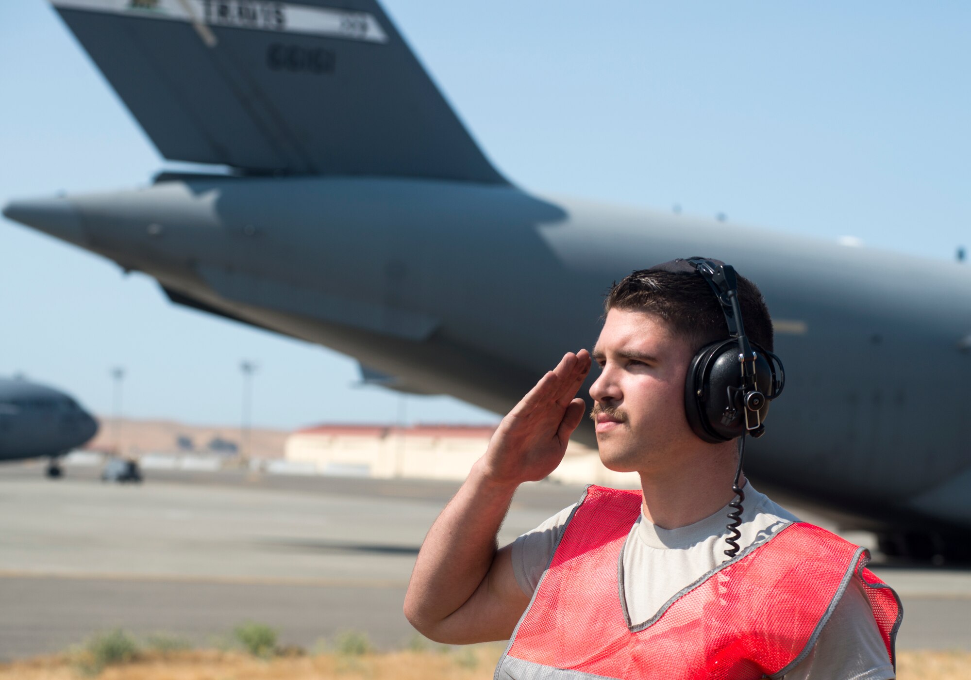 Senior Airman Kyle Lake, 60th Aircraft Maintenance Squadron crew chief, salutes a C-5M Super Galaxy as it taxis down the flightline on Aug. 11, 2018, at Travis Air Force Base, Calif. The 349th and 60th AMXS work together to launch aircraft in a seemless active duty and Air Force Reserve integration.