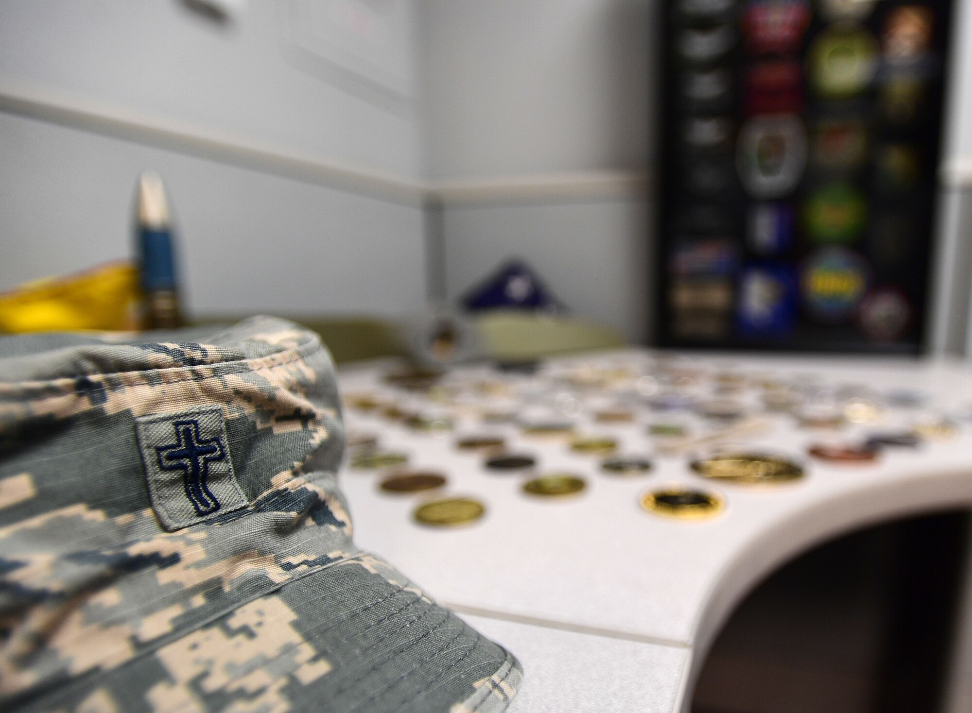 Chaplain Matthew’s hat sits alongside his military coins and patches accumulated from 22 years in the U.S. Army as an infantryman, honor guardsman, and Apache helicopter pilot prior to becoming a U.S. Air Force Chaplain. He now leverages his combat experience to further help combat Airmen at Creech Air Force Base, Nev. (U.S. Air Force photo by Senior Airman Christian Clausen)