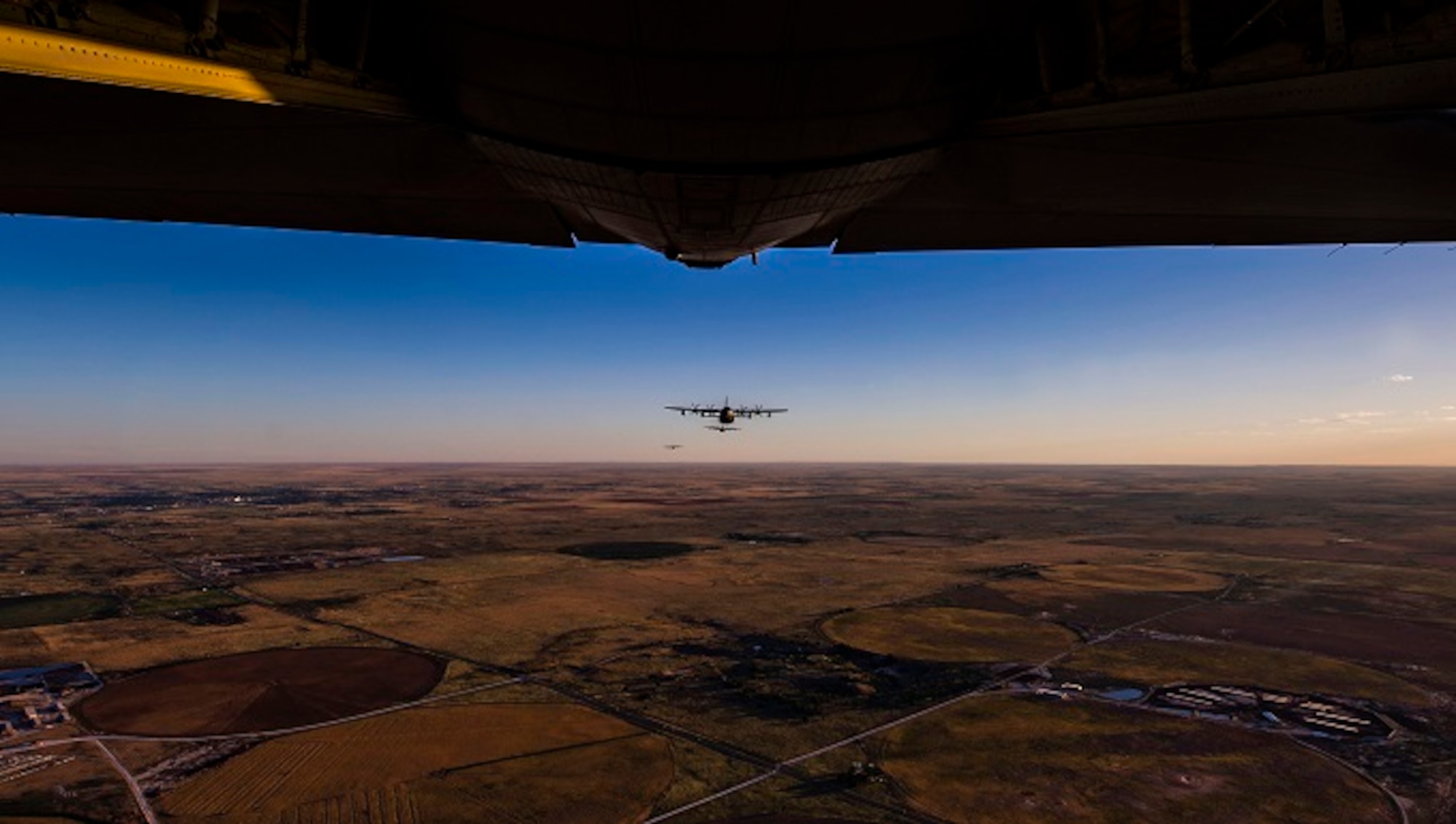 The tail of a plane shows as another plane flies over the New Mexico plains