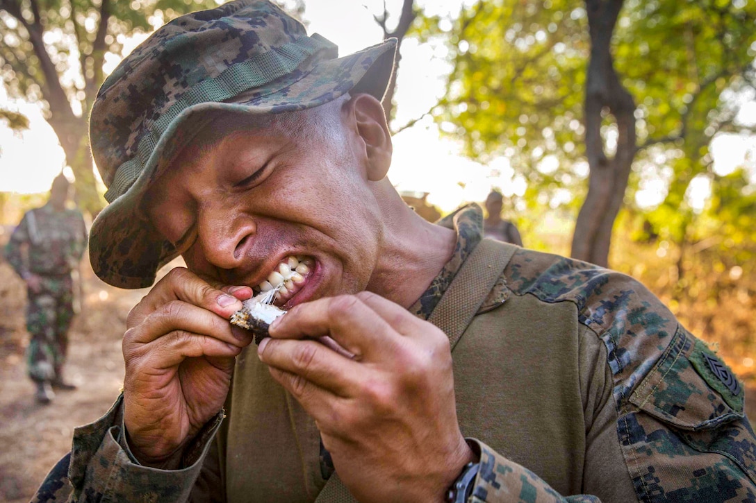 A Marine bites into a cooked snake.