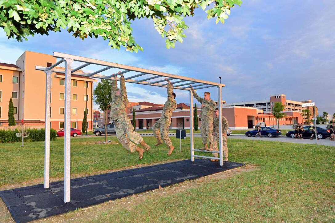 Soldiers navigate from bar to bar on the horizontal ladder during the obstacle course.