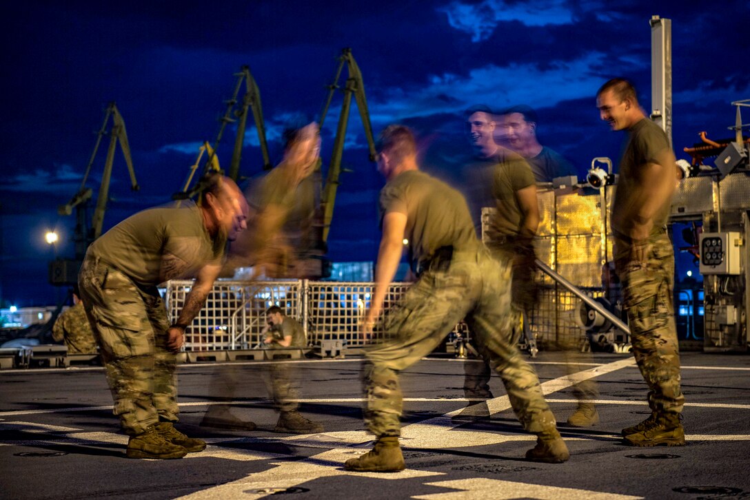 Soldiers play hackysack on a navy ship.