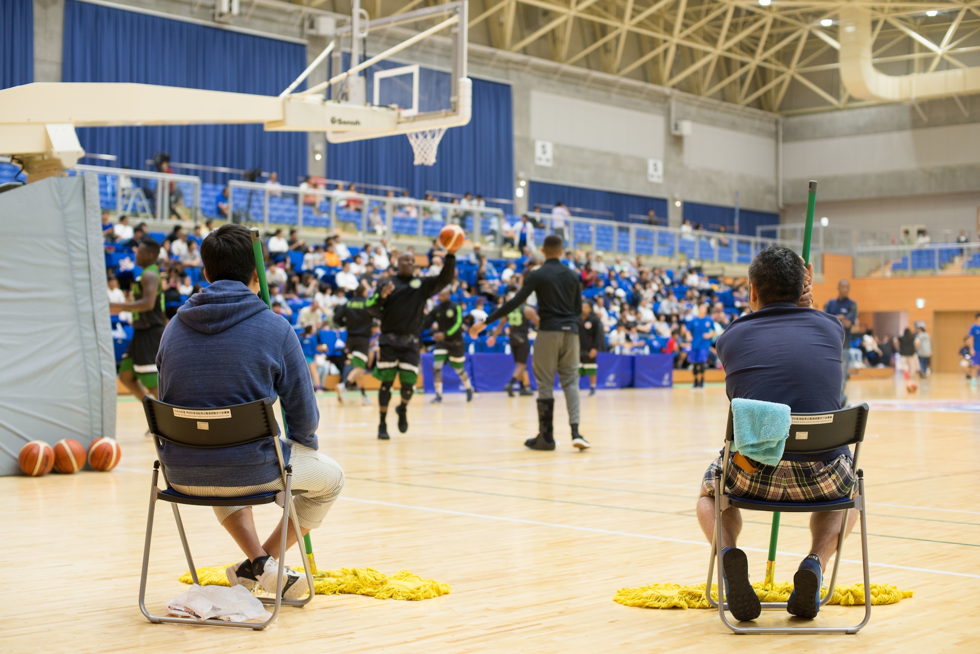 Sweepers sit ready to wipe the floor clean during the Aomori Wat’s and Misawa Jets exhibition game at the Misawa International Sports Center in Misawa City, Japan, Aug. 18, 2018. The sweepers ran out at every timeout, foul, referee break and period intermission keeping the floor clean of sweat, tears and sometimes blood. The game’s organizers sought to improve U.S.-Japan relations while fostering positive community engagement with Misawa Air Base’s host nation neighbors. (U.S. Air Force photo by Tech. Sgt. Benjamin W. Stratton)