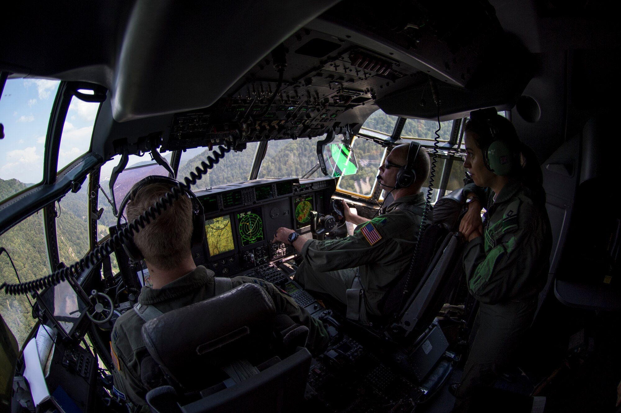 U.S. Air Force Capt. Bryant Bailey, 37th Airlift Squadron pilot, and Lt. Col. Alex Miller, 37th AS director of operations, fly a C-130J Super Hercules aircraft over Romania as Romanian air force Lt. Cmdr. Nicoleta Udrescu, Air Base 90 Otopeni pilot, watches during exercise Carpathian Summer 2018, Aug. 21, 2018. The purpose of the bilateral training exercise is to enhance interoperability and readiness by conducting combined air operations with the Romanian air force. (U.S. Air Force photo by Senior Airman Devin Boyer)