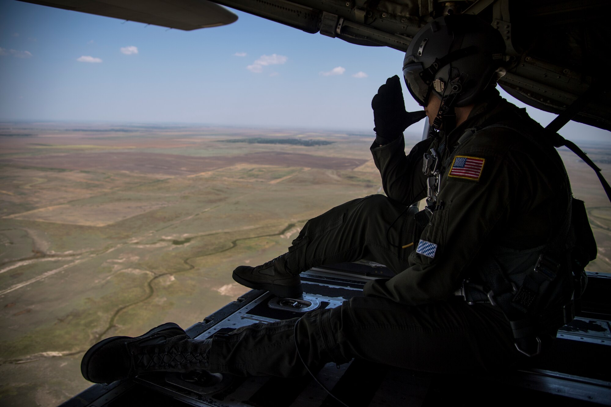 U.S. Air Force Staff Sgt. Matthew Fry, 37th Airlift Squadron loadmaster, sits on the ramp of a C-130J Super Hercules aircraft as it flies over Romania during exercise Carpathian Summer 2018, Aug. 21, 2018. Carpathian Summer is a bilateral training exercise designed to enhance interoperability and readiness by conducting combined air operations with the Romanian air force. (U.S. Air Force photo by Senior Airman Devin Boyer)