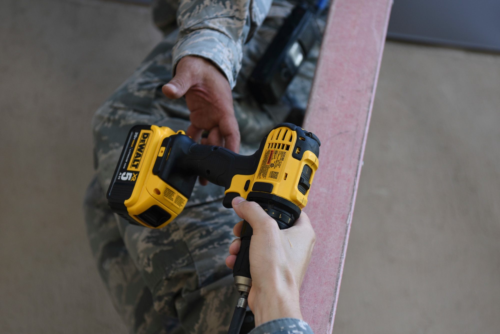U.S. Air Force Staff Sgt. Matthew Brown (bottom), 8th Civil Engineer Squadron structural journeyman, hands a drill to Tech. Sgt. Darlwin Langit, (top), 8th CES structural noncommissioned officer in charge, at Kunsan Air Base, Republic of Korea, Aug. 22, 2018. Airmen from the 8th Fighter Wing cleaned-up loose items, filled sand bags, and took other preparatory actions as Typhoon Soulik approaches the Korean peninsula. (U.S. Air Force photo by Senior Airman Savannah L. Waters)