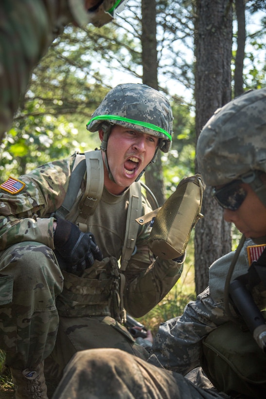 A soldier yells instructions to a fellow squad members to prepare their gas mask.