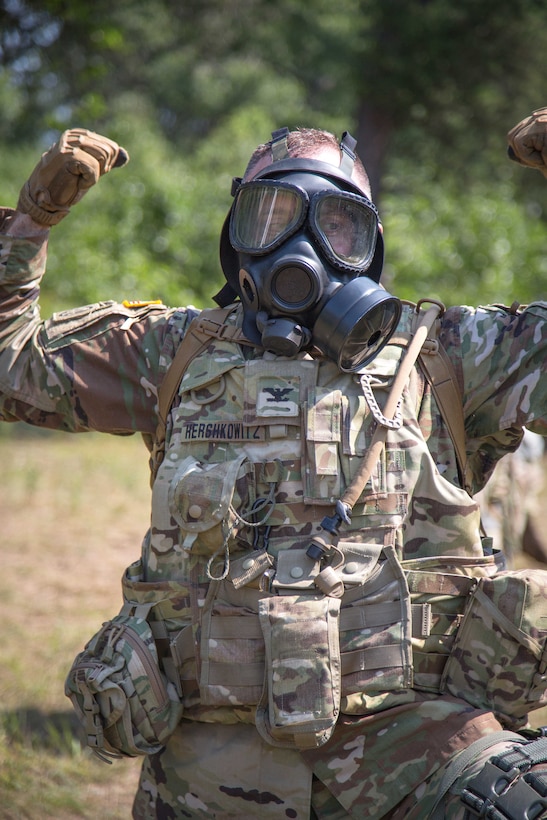The commander signals “gas” to his soldiers during a simulated attack.