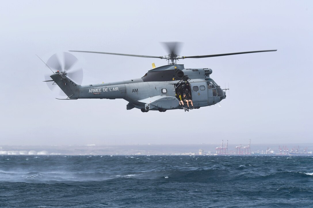 U.S. airmen prepare to jump out of a French SA 330 Puma helicopter.