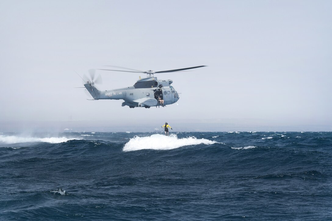 A U.S. airman jumps out of a French SA 330 Puma helicopter.