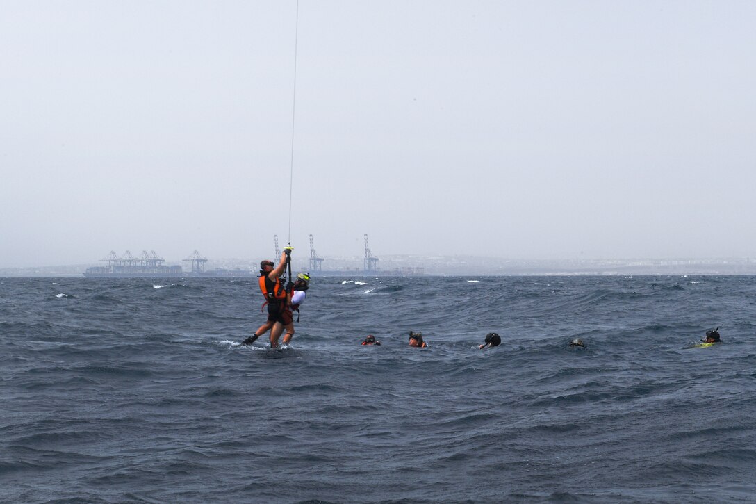 U.S. airmen are hoisted up into a French SA 330 Puma helicopter during a personnel recovery training.