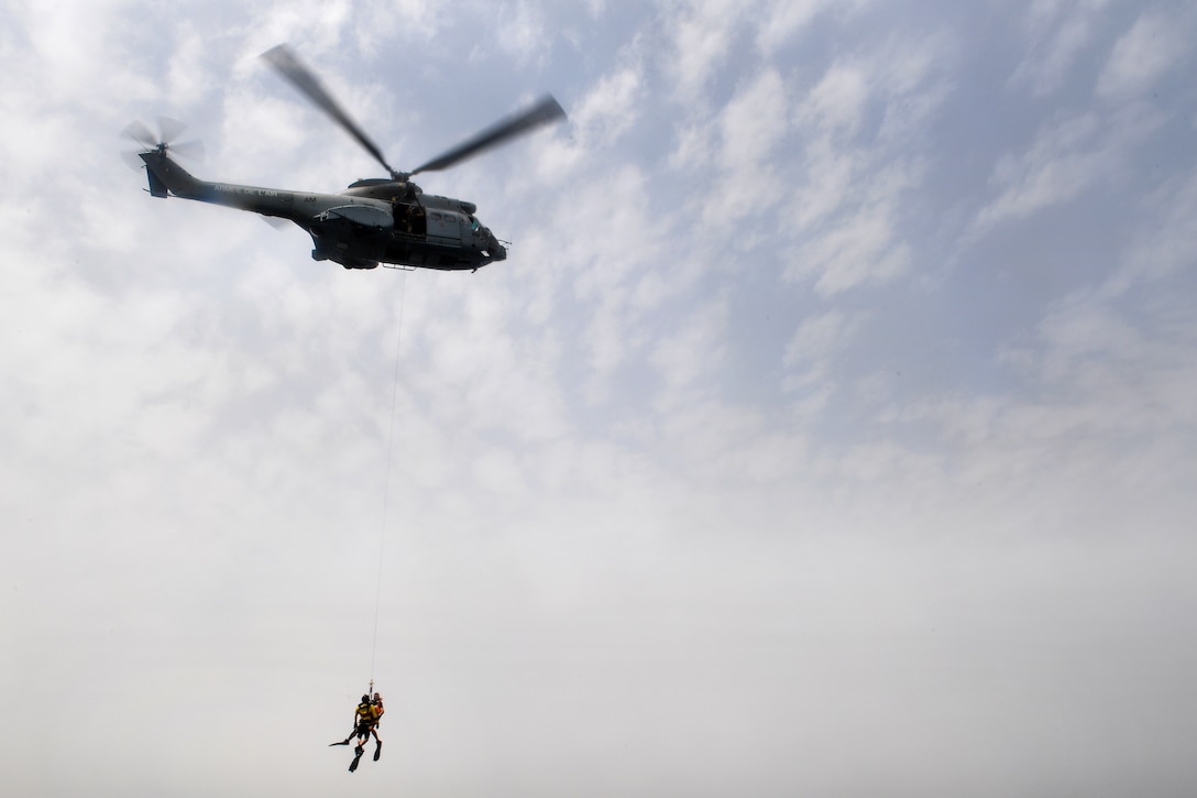 U.S. airmen are hoisted up into a French SA 330 Puma helicopter during a personnel recovery training.