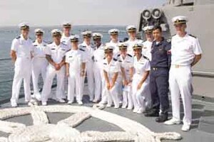 A group of ROTC midshipmen pose for a photo on board a ship.