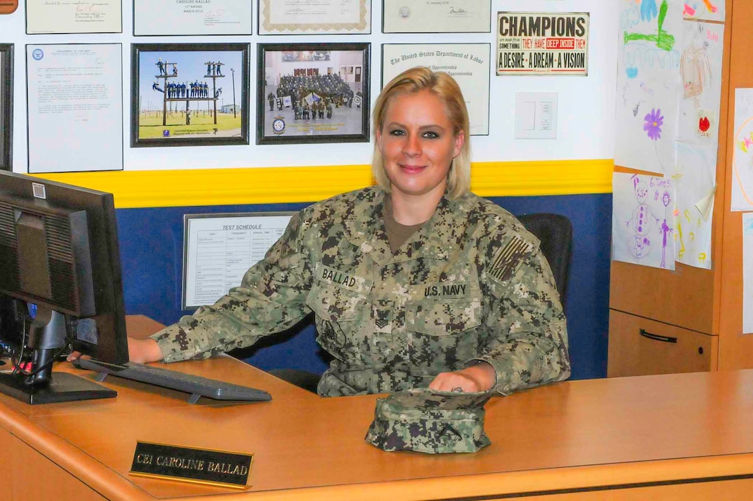 A Navy Petty Officer sits at her desk.