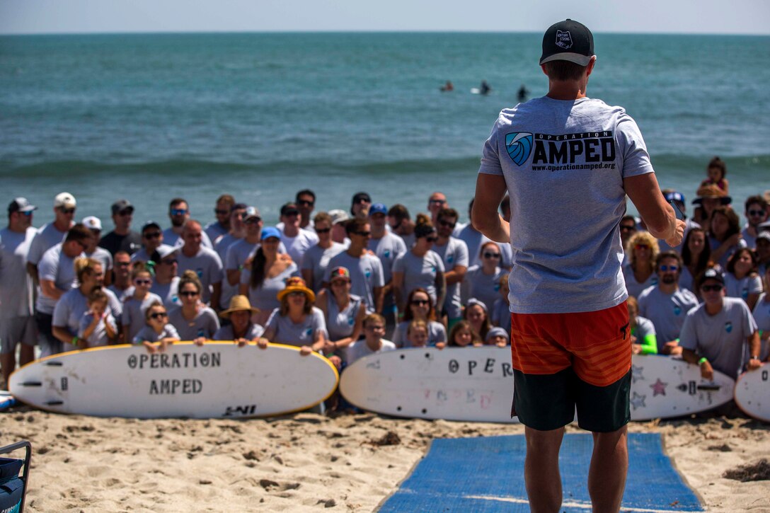 Recovering service members, veterans, volunteers and their loved ones prepare for a group photo during the 12th Annual Operation Amped Surf Camp at San Onofre Beach at Marine Corps Base Camp Pendleton, California, Aug. 18, 2018. Operation Amped is a nonprofit organization that supports wounded, ill and injured service members and veterans throughout their recovery.