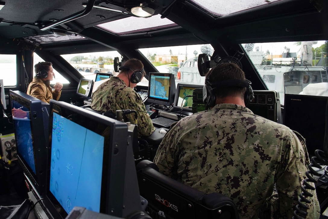 Sailors stand watch in the pilothouse aboard a Mark VI patrol boat.