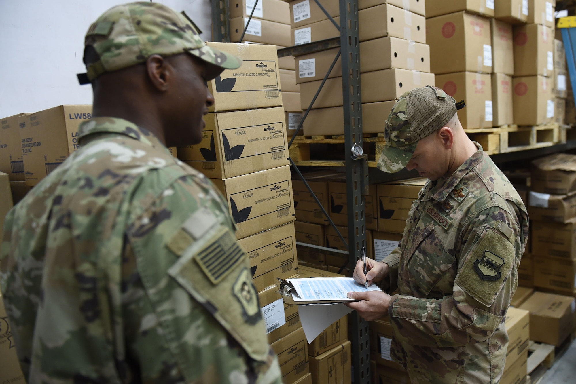 Two Airmen check temperatures in a food storage container