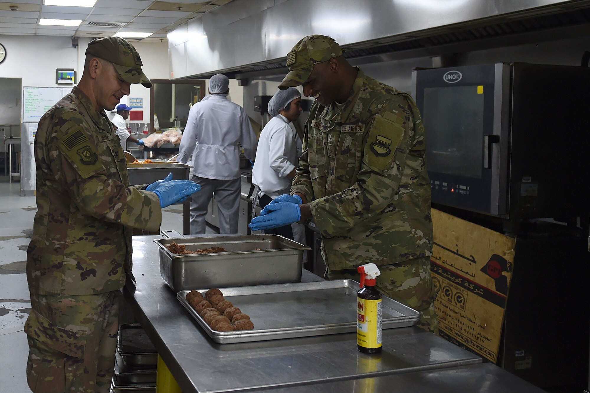 Two Airmen roll meat into meatballs