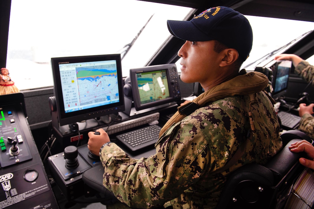 A sailor monitors computer screens while standing watch as the coxswain aboard a Mark VI patrol boat.