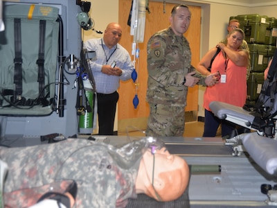 Sgt. 1st Class Lee Hockersmith, U.S. Army Medical Department Center and School instructor and NCO in charge of the Critical Care Flight Paramedic Program at Joint Base San Antonio-Fort Sam Houston, talks to San Antonio community members and civic leaders gathered in a helicopter medical evacuation simulation lab during the Fort Sam Houston Military Medical Tour Aug. 10. The purpose of the tour, a joint effort between Brooke Army Medical Center Public Affairs and the City of San Antonio Office of Military and Veteran Affairs, was to showcase the contributions of military medicine and its impact on the San Antonio community.