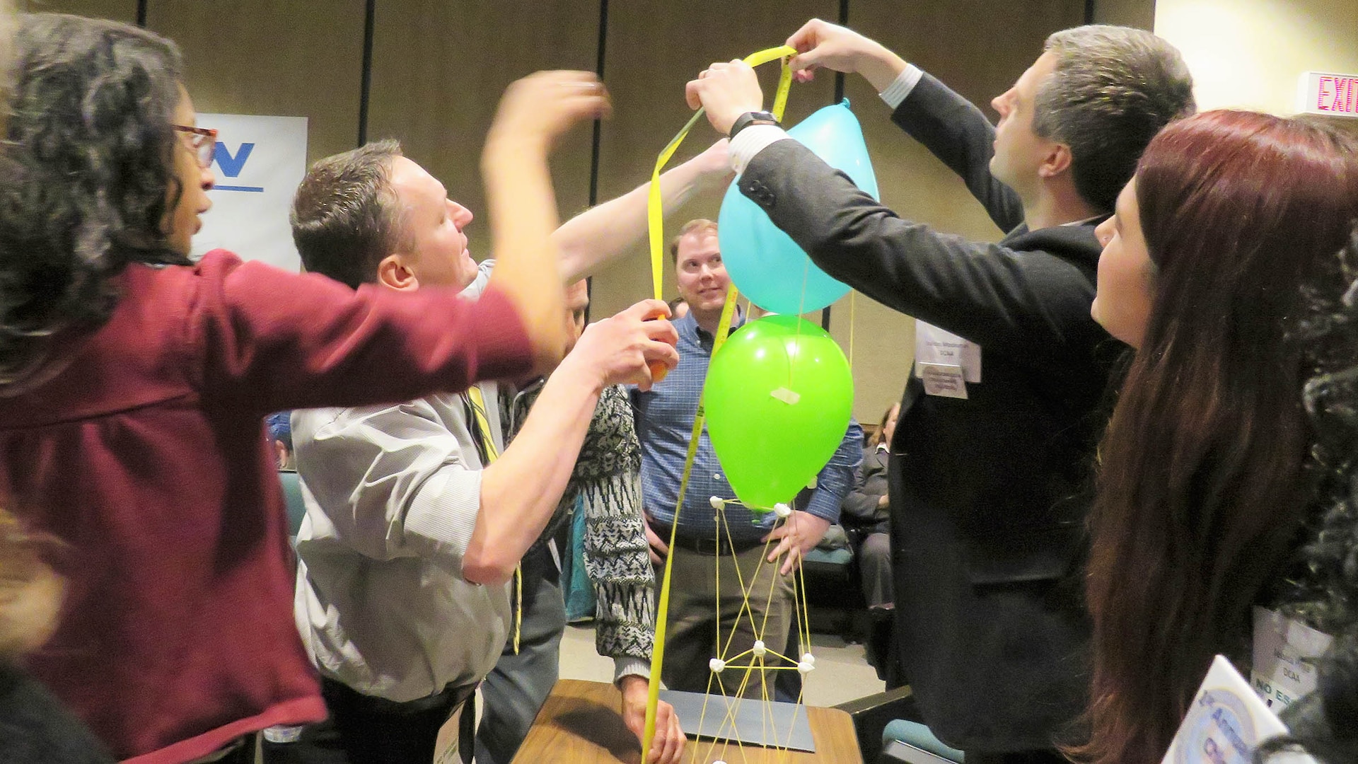 DCMA and DCAA employees build a tower with string and ballons as a team-building exercise.