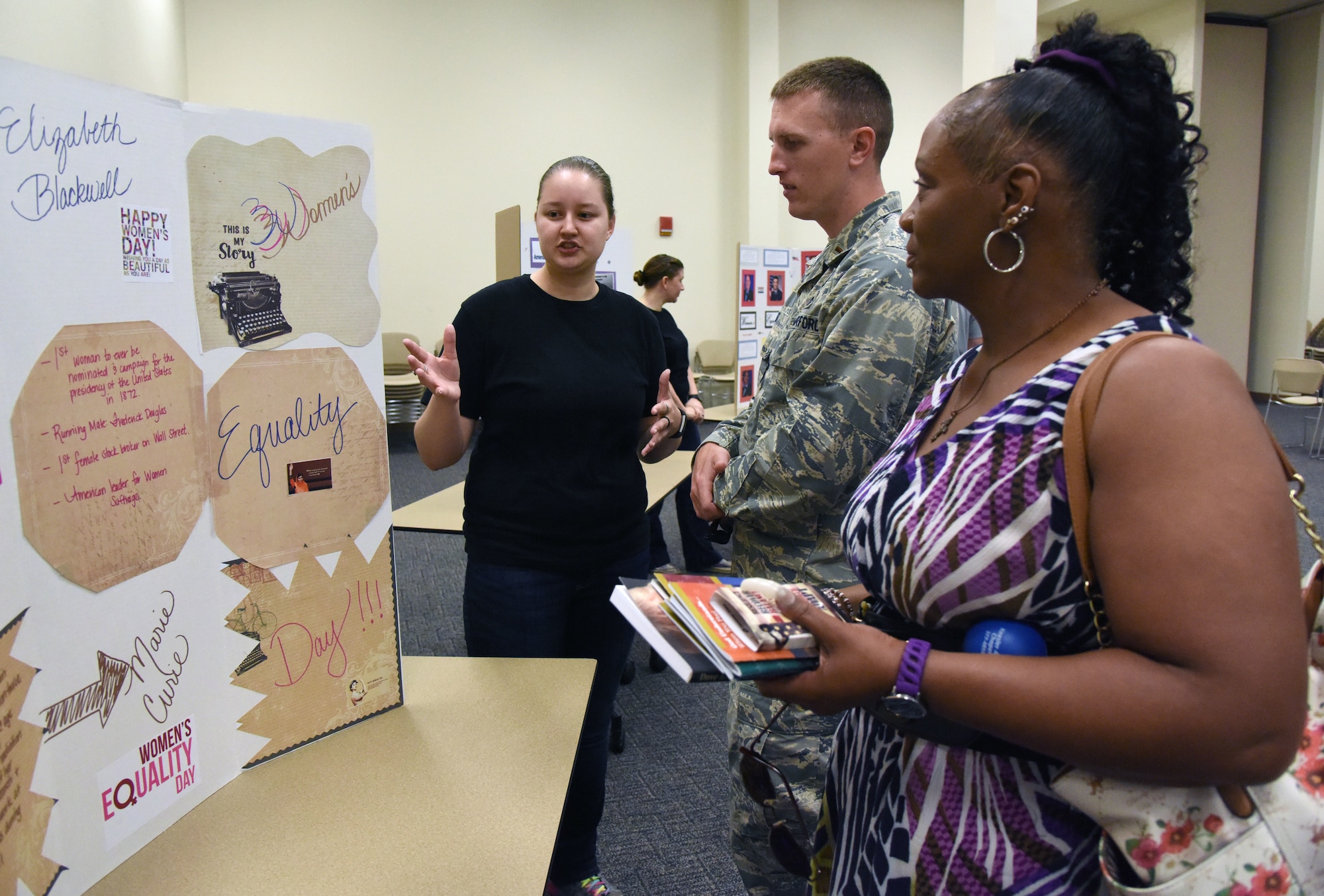 U.S. Air Force Senior Airman Savannah Slaughter, 81st Comptroller Squadron financial analyst, briefs 2nd Lt. Bryan Case, 81st CPTS deputy flight commander, and Janice Carr-Scott, 81st CPTS accounting technician, on educational panels during the 81st Training Wing Women's Equality Day Observance at the Roberts Consolidated Aircraft Maintenance Facility at Keesler Air Force Base, Mississippi, Aug. 21, 2018. In 1971, the U.S. Congress designated Aug. 26 as Women�s Equality Day. (U.S. Air Force photo by Kemberly Groue)