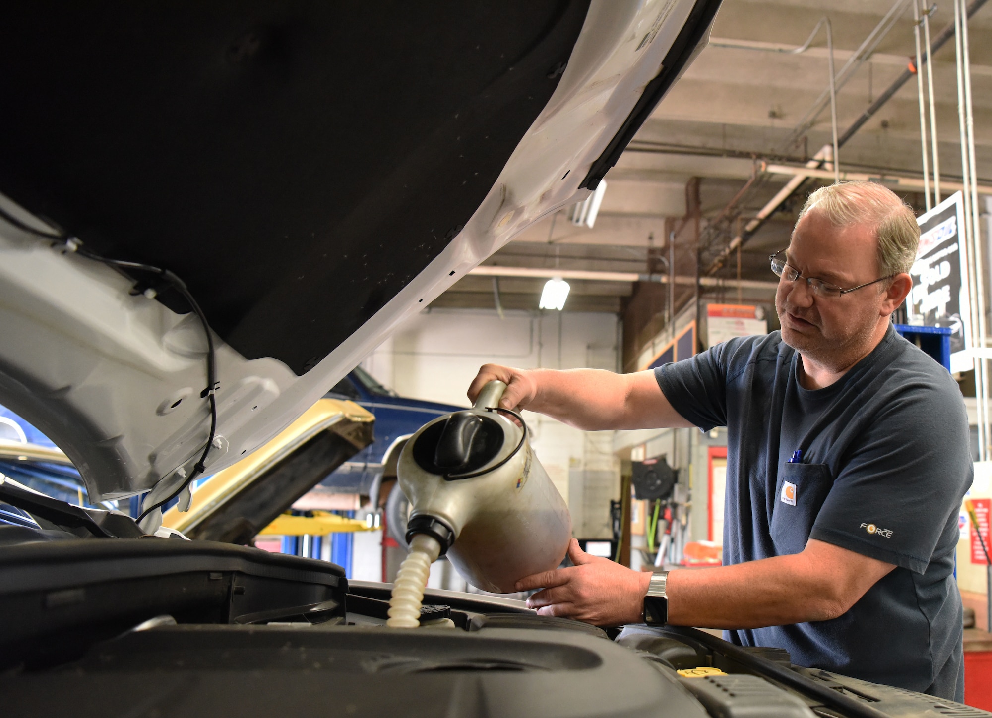 Paul Balcom, the auto hobby shop manager, pours oil into the engine of a vehicle at Ellsworth Air Force Base, S.D., Aug. 15, 2018. The mechanics at the hobby shop are here to help Airmen and their families with their automotive repair needs and to help car enthusiasts with their projects. (U.S. Air Force Photo by Airman 1st Class Thomas Karol)
