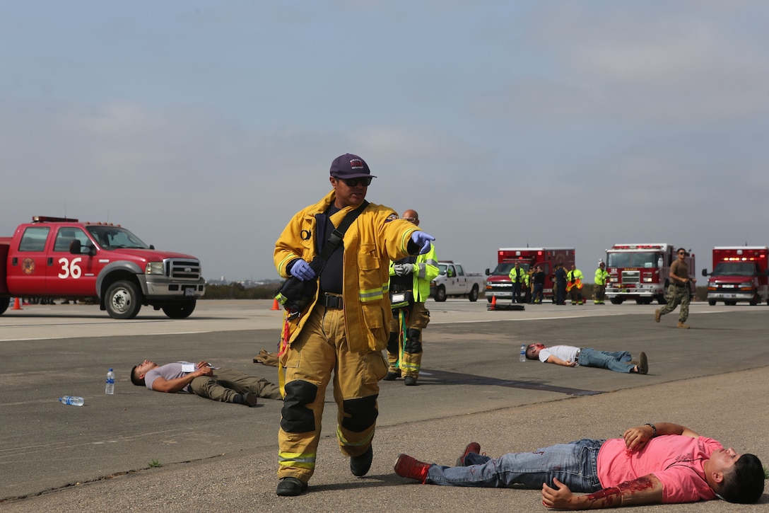 A firefighter with the Marine Corps Air Station Miramar Fire Department directs personnel to help victims during an exercise at MCAS Miramar, Aug 16. 2018. Emergency response exercises are conducted to rehearse response times, validate existing standard operating procedures, fulfill annual training requirements and validate the effectiveness of MCAS Miramar emergency services. (U.S. Marine Corps photo by Sgt Daniel Auvert.)