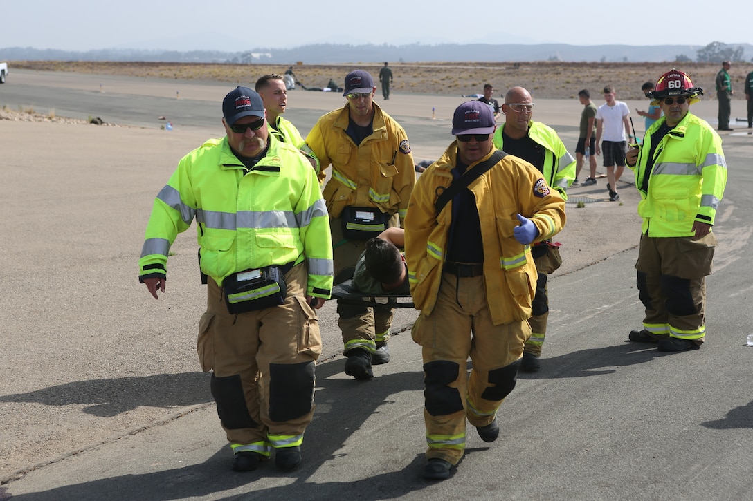 Firefighters with the Marine Corps Air Station Miramar Fire Department escort a victim to the triage center during an exercise at MCAS Miramar, Aug 16. 2018. Emergency response exercises are conducted to rehearse response times, validate existing standard operating procedures, fulfill annual training requirements, and validate the effectiveness of MCAS Miramar emergency services. (U.S. Marine Corps photo by Sgt. Daniel Auvert.)